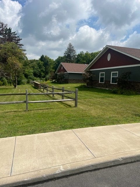 A peaceful suburban scene with houses, a wooden fence, and a neatly maintained lawn under a partly cloudy sky.