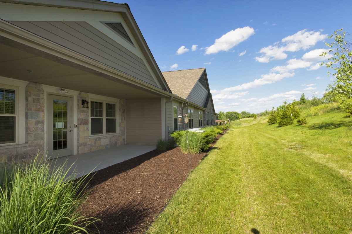 A view of modern residential homes with a well-maintained lawn and garden under a clear blue sky.