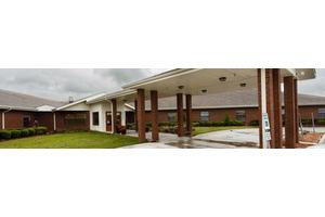 A brick building with an entrance and overhanging roof on a cloudy day.