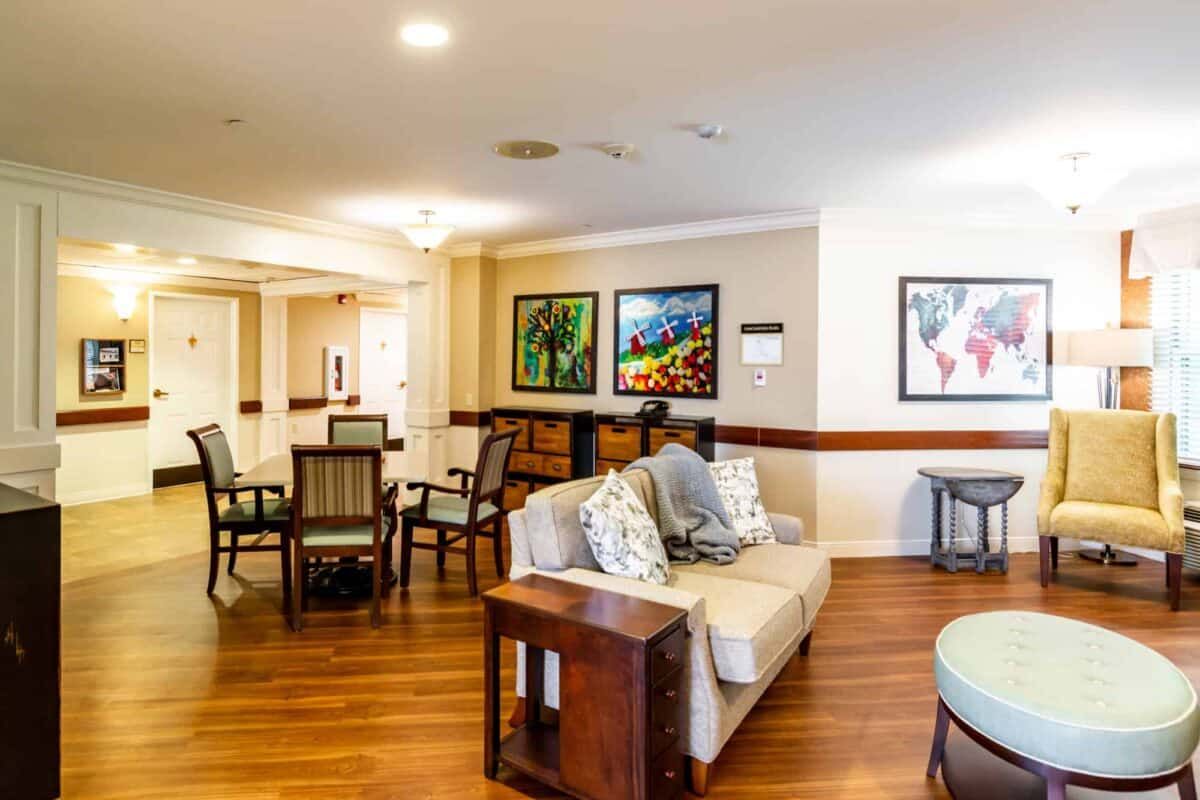 A cozy living room with a sofa, chairs, and vibrant artwork on the walls.