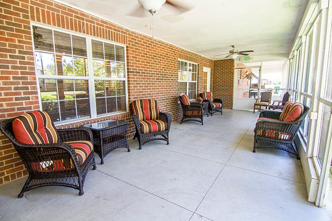 A spacious patio area with comfortable chairs and a brick wall backdrop.