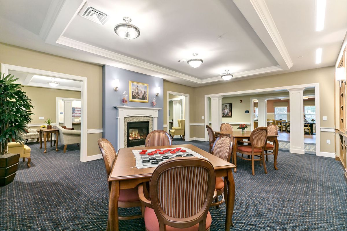 A cozy living room with a central fireplace, furnished with tables and chairs.