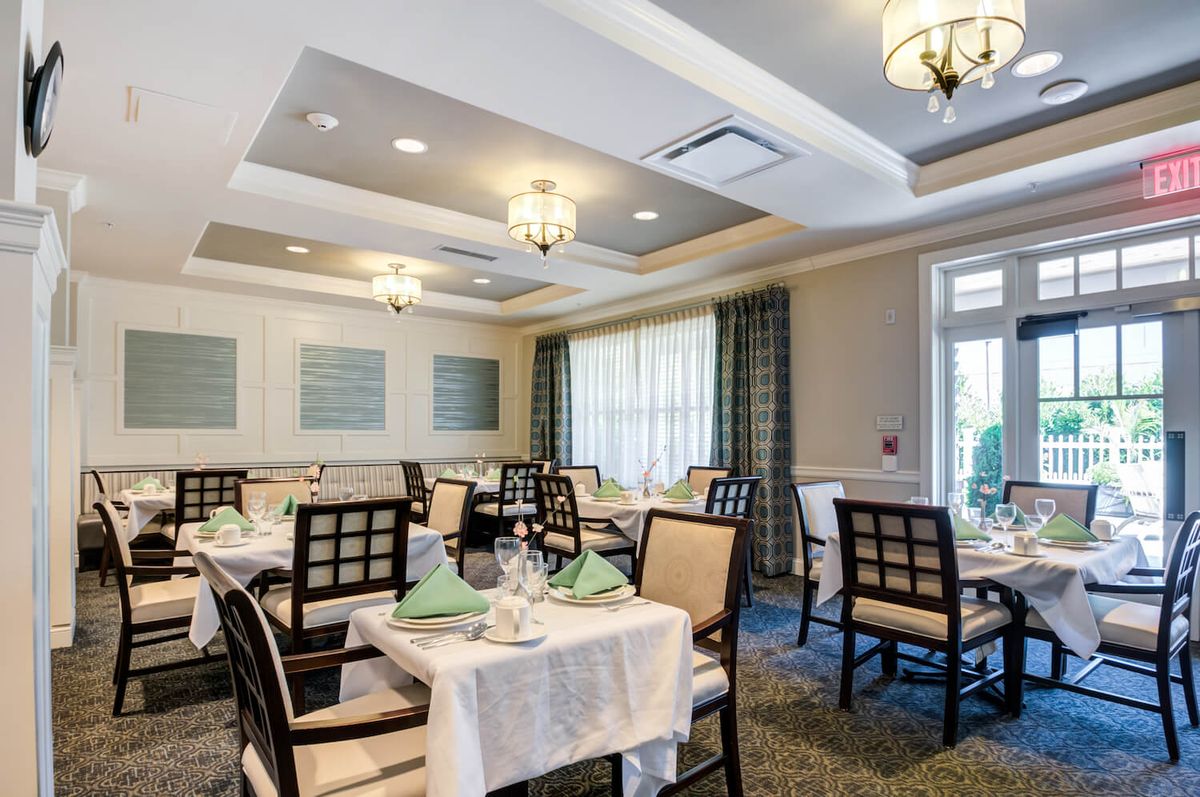 An elegant dining room setup with beautifully arranged tables and chairs, complete with chandeliers and soft lighting.