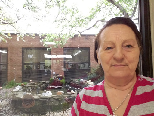 A woman takes a selfie indoors with a view of a garden through the window.