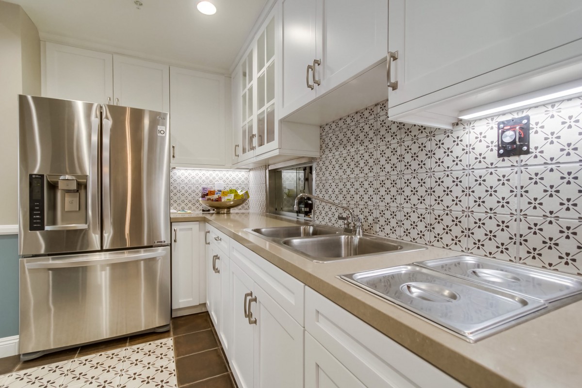 A modern kitchen with white cabinets, stainless steel appliances, and a decorative tile backsplash.