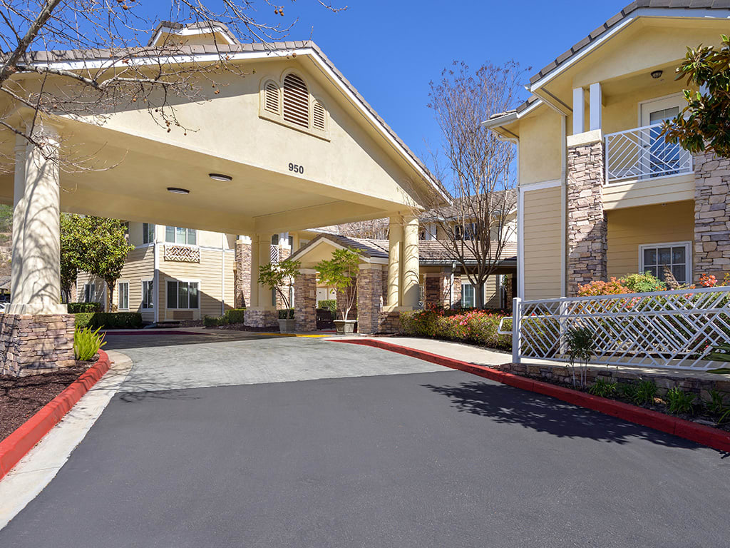 A residential building entrance with a covered driveway under a clear blue sky.