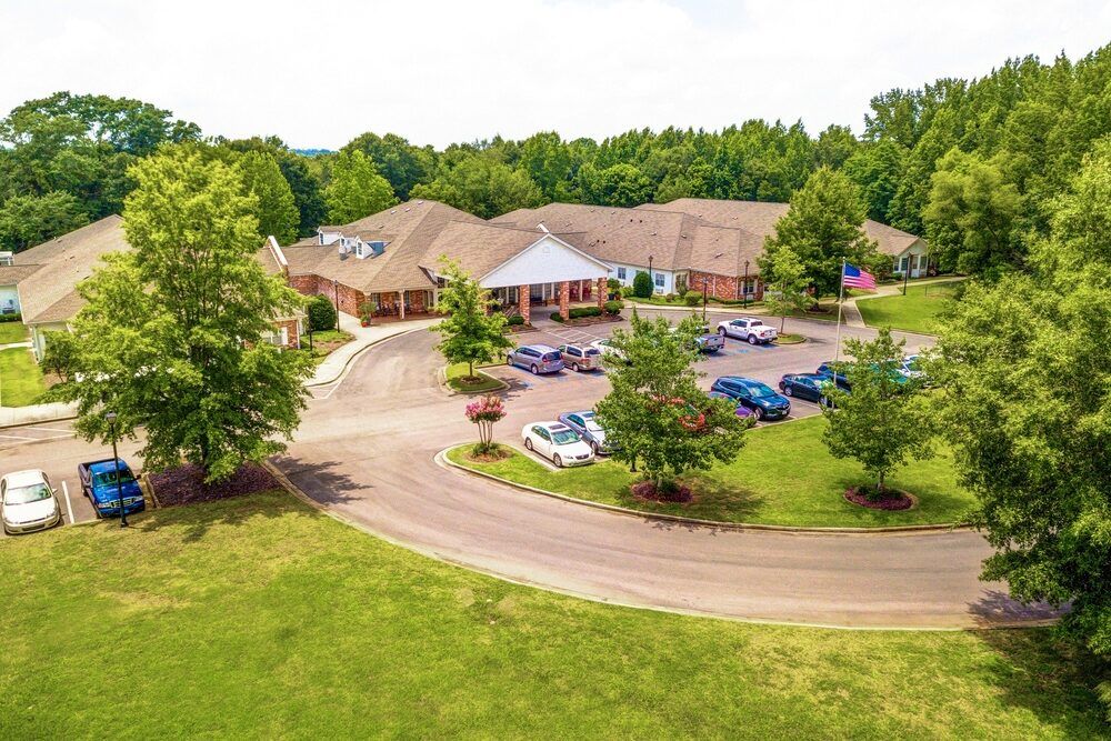 Aerial view of a building with a surrounding parking lot and lush greenery.