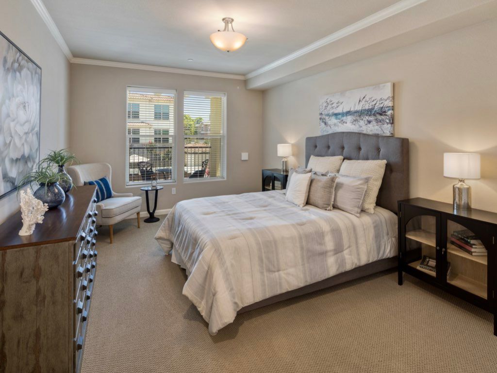 A well-decorated bedroom with a comfortable bed, stylish furniture, and large windows.