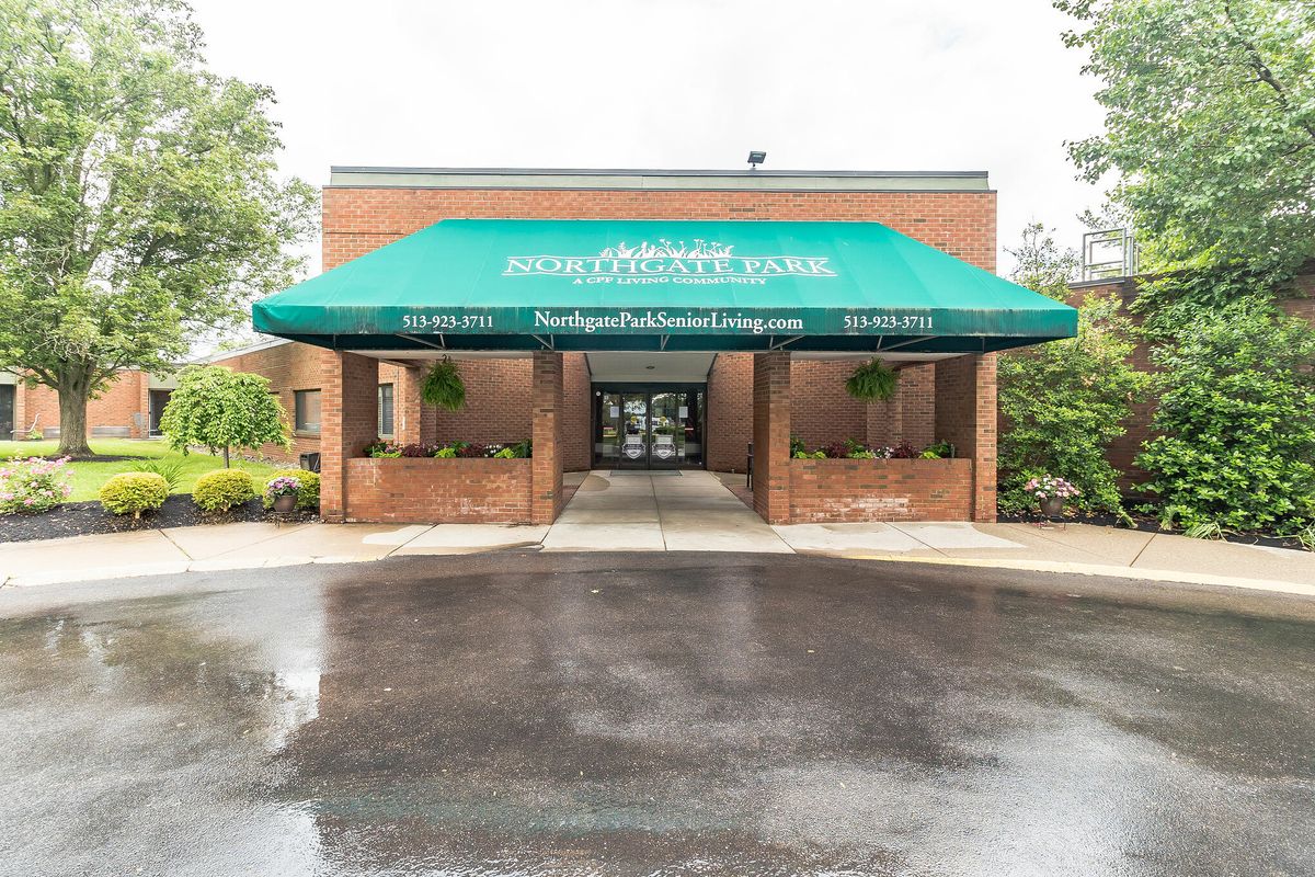 Entrance of a building with a green awning and brick exterior.