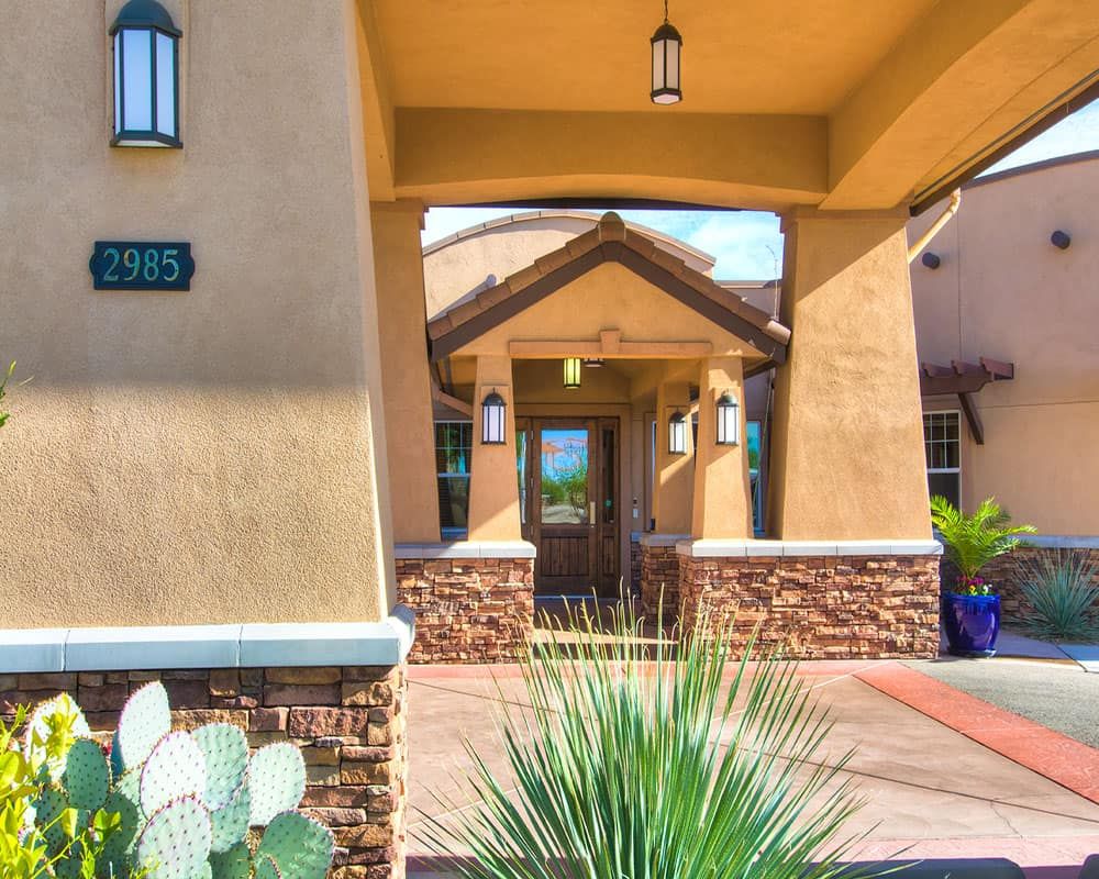 Entrance of a building featuring stucco walls and desert landscaping.