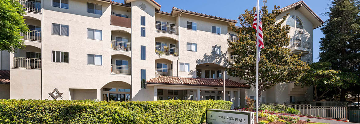 A multi-story residential apartment building with balconies and a landscaped front.