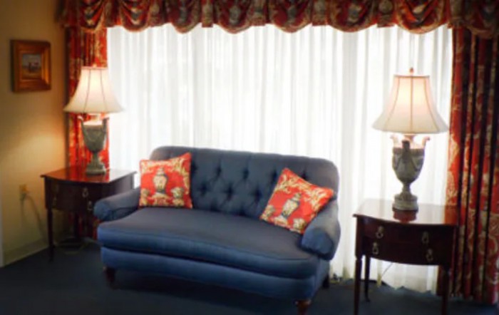 A cozy living room setup with a blue sofa, decorative cushions, and elegant lamps flanking either side.