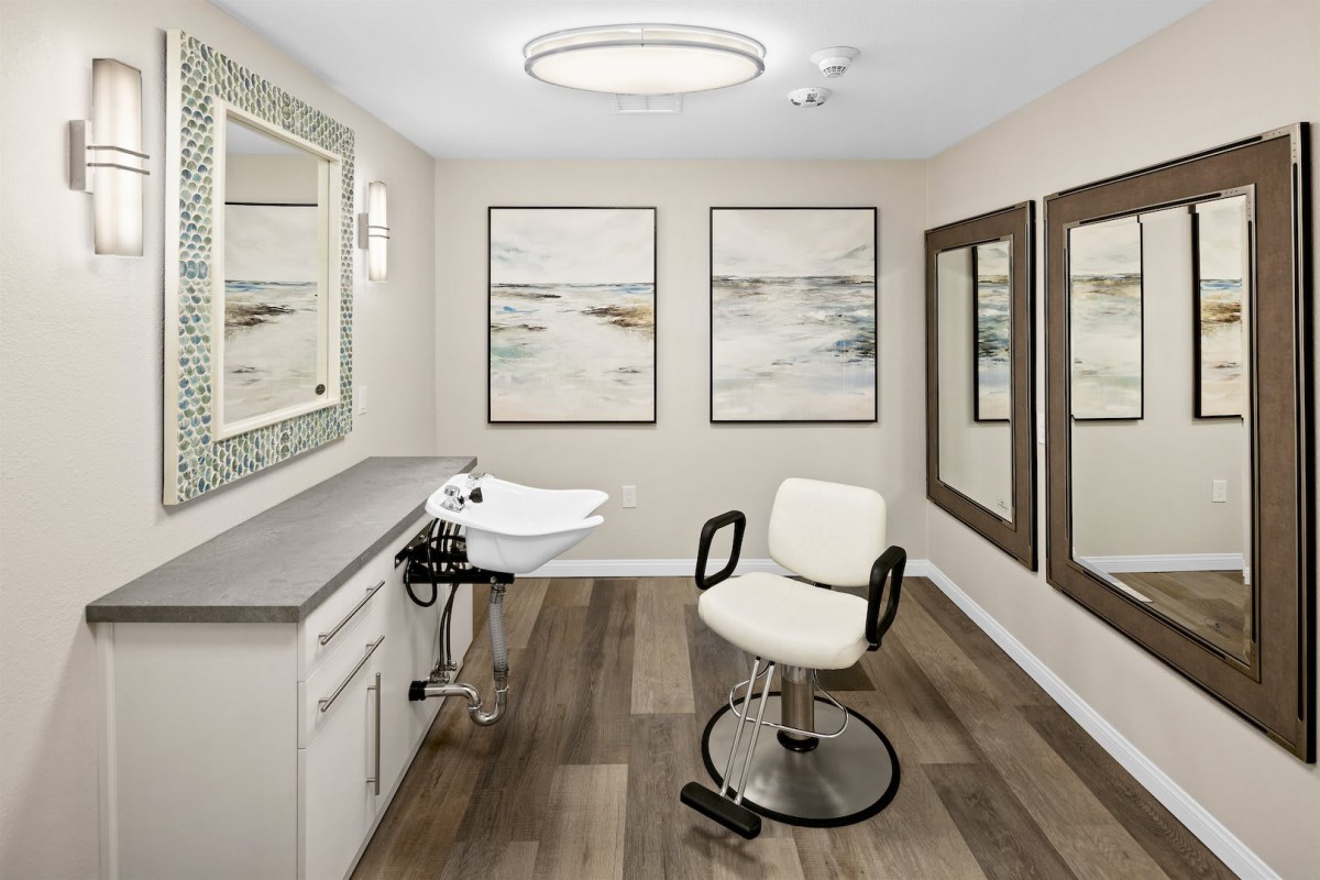 A modern hair salon interior with a barber chair, sink, and elegant wall art.