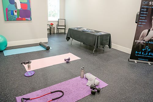A quiet yoga room with mats, dumbbells, and water bottles ready for a workout session.