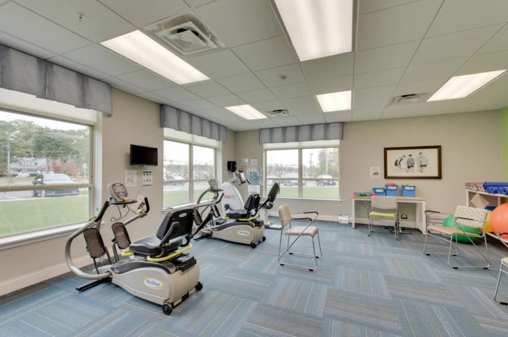 A well-lit exercise room with various gym equipment, including stationary bikes and a treadmill.