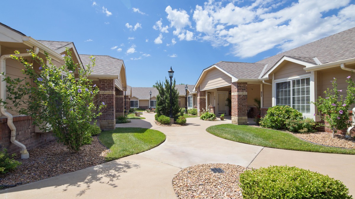 A peaceful residential neighborhood with neatly maintained houses and gardens under a blue sky.