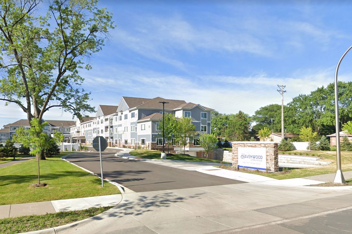 Entrance to a modern apartment complex with surrounding greenery.