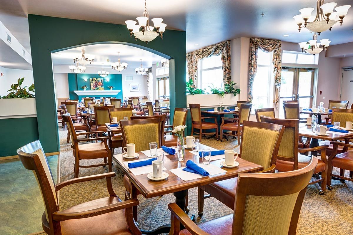 A well-arranged dining area with elegantly set tables, featuring comfortable chairs and chic chandeliers.