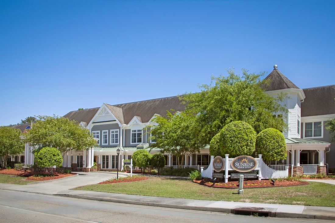 A picturesque hotel building surrounded by well-maintained landscaping under a clear blue sky.