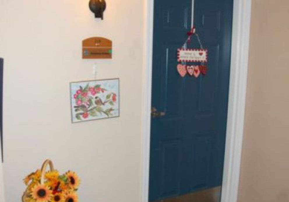 A cozy interior featuring a blue door with wall decorations and a vase of sunflowers.