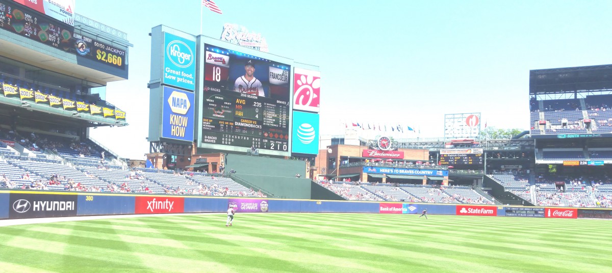 A view of a baseball stadium with a large scoreboard displaying player information.