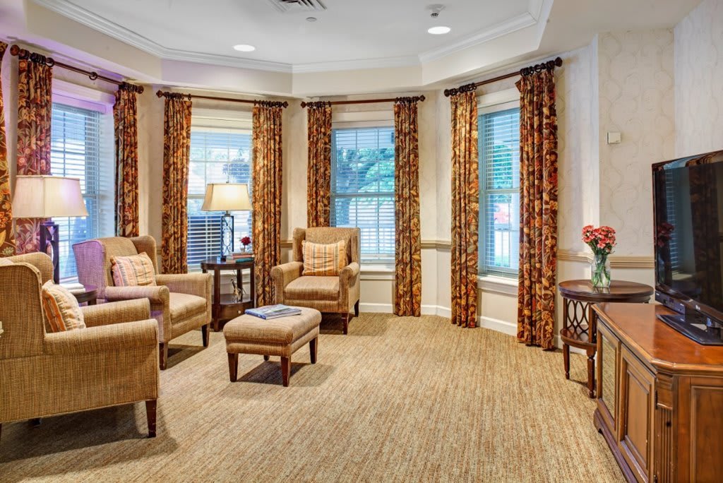 A cozy living room with comfortable chairs and large windows adorned with curtains.