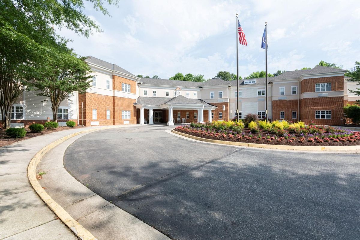 A beautiful building with an entrance driveway and flags displayed at the front.