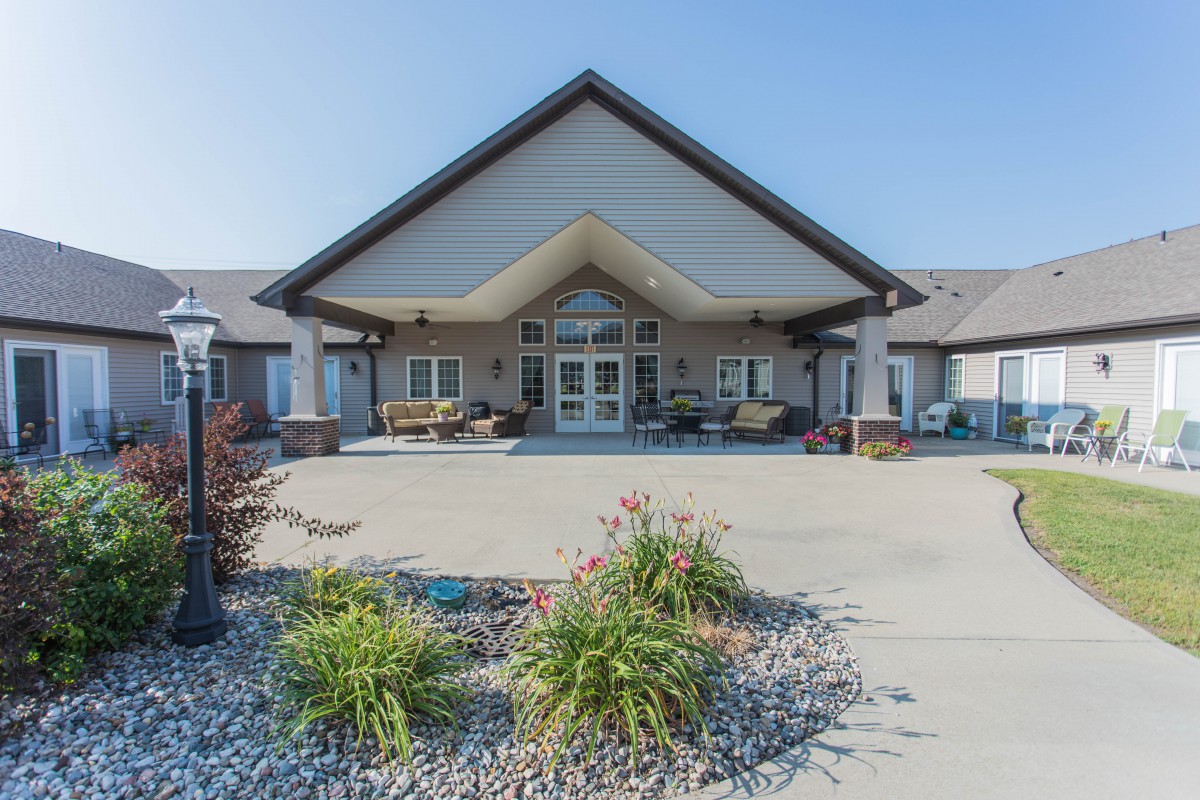 A well-maintained building entrance with landscaped surroundings and a paved walkway.