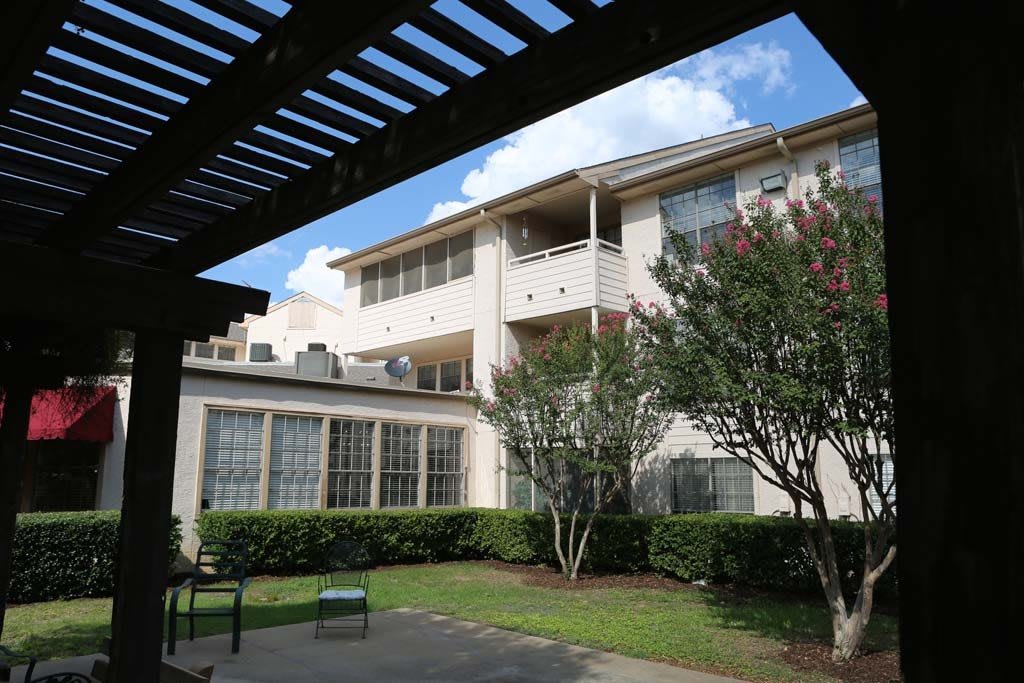 A view of an apartment building with a garden area and blue sky.