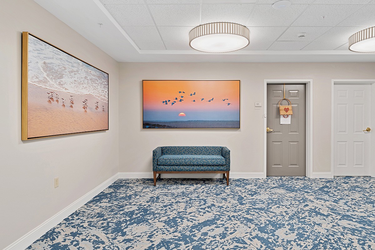 A modern hallway with artwork, a bench, and elegant lighting.
