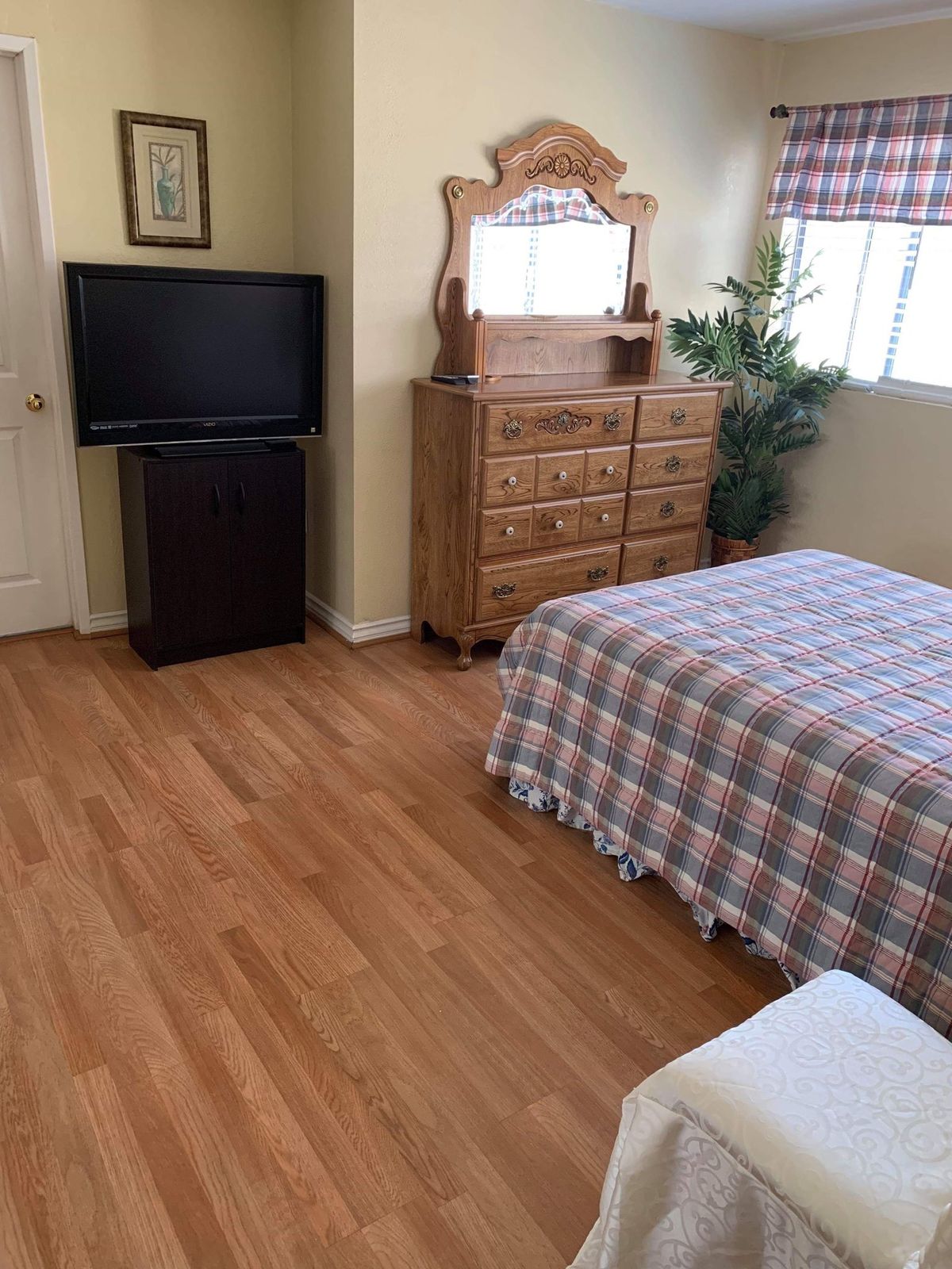 A cozy bedroom with wooden flooring, a dresser, and a television.