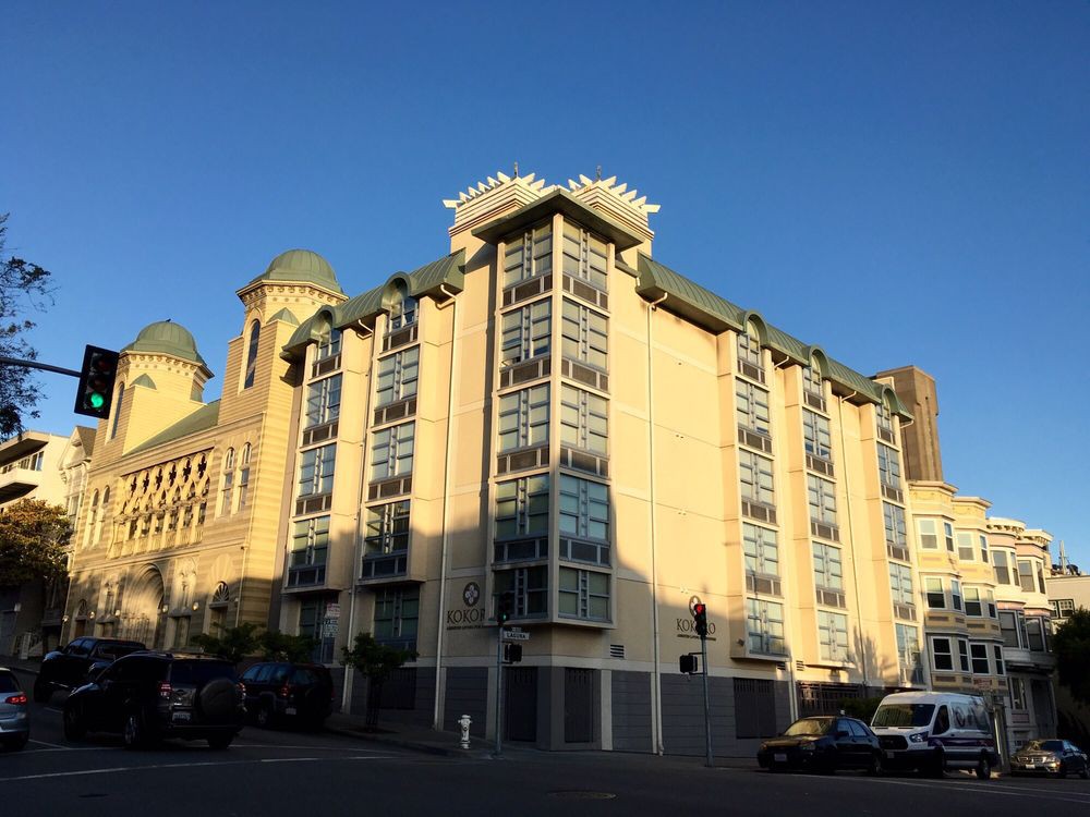 A modern urban building illuminated by sunlight against a clear blue sky.