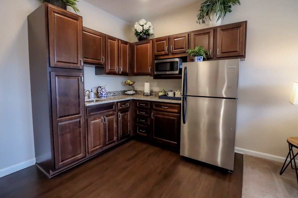 A modern kitchen with dark wooden cabinets and stainless steel appliances.