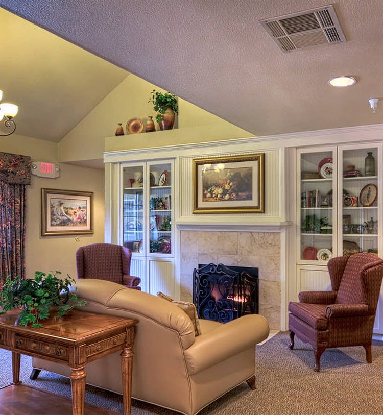 A cozy living room with a fireplace, comfortable seating, and decorated shelves.