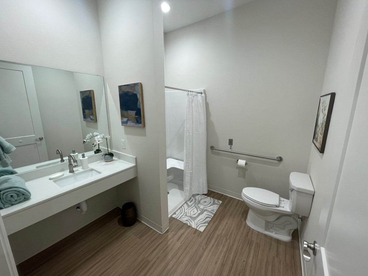 A modern and clean bathroom with a sink, mirror, toilet, and shower area.