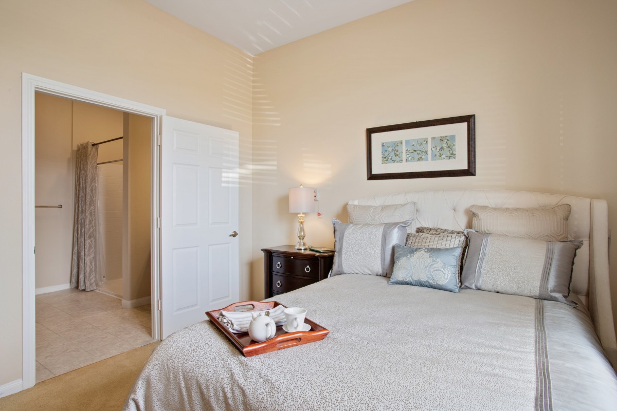 A cozy and well-decorated bedroom with a neatly made bed, bedside table, and a framed artwork above the headboard.