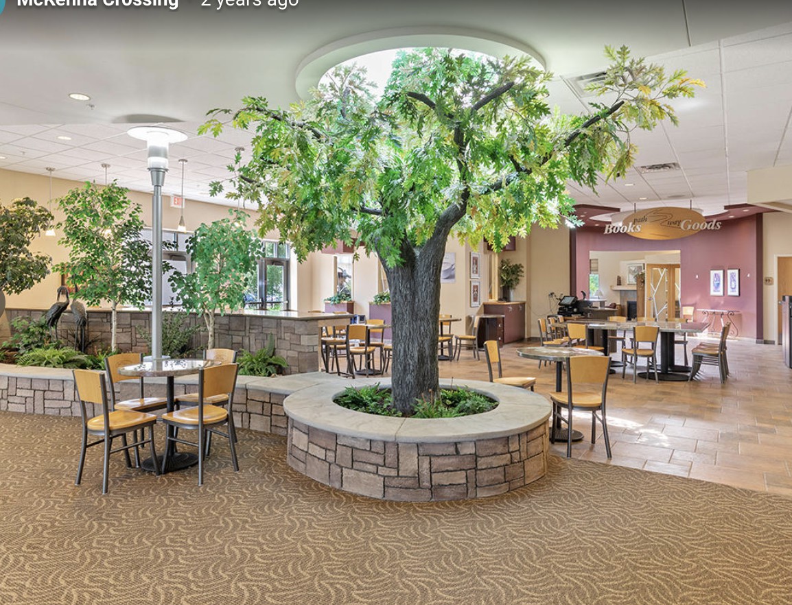 An inviting indoor restaurant space with a central artificial tree and comfortable seating.