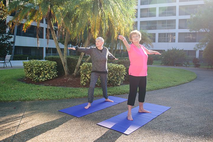 Two people practicing yoga outdoors on mats.