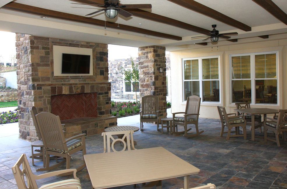 A cozy outdoor patio with seating, a fireplace, and ceiling fans provides a comfortable setting for relaxation.
