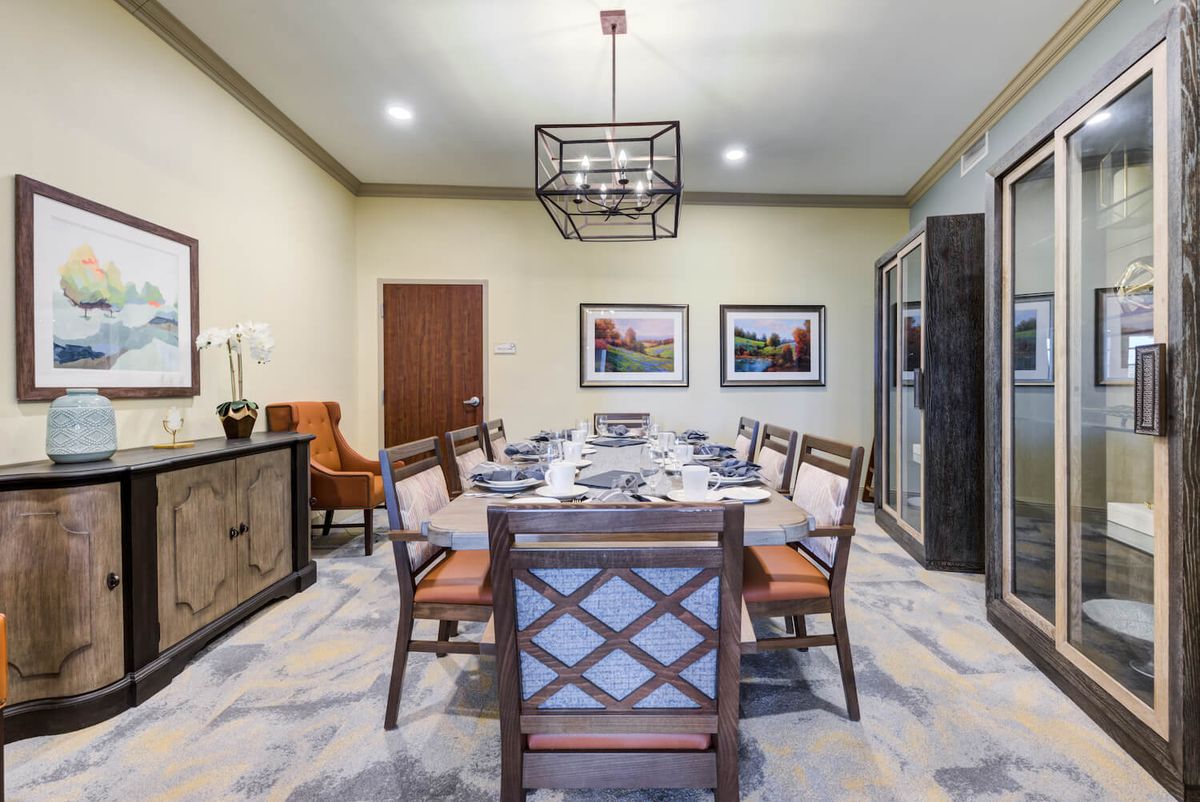 A modern dining room with a stylish table and chairs, featuring elegant lighting and wall art.