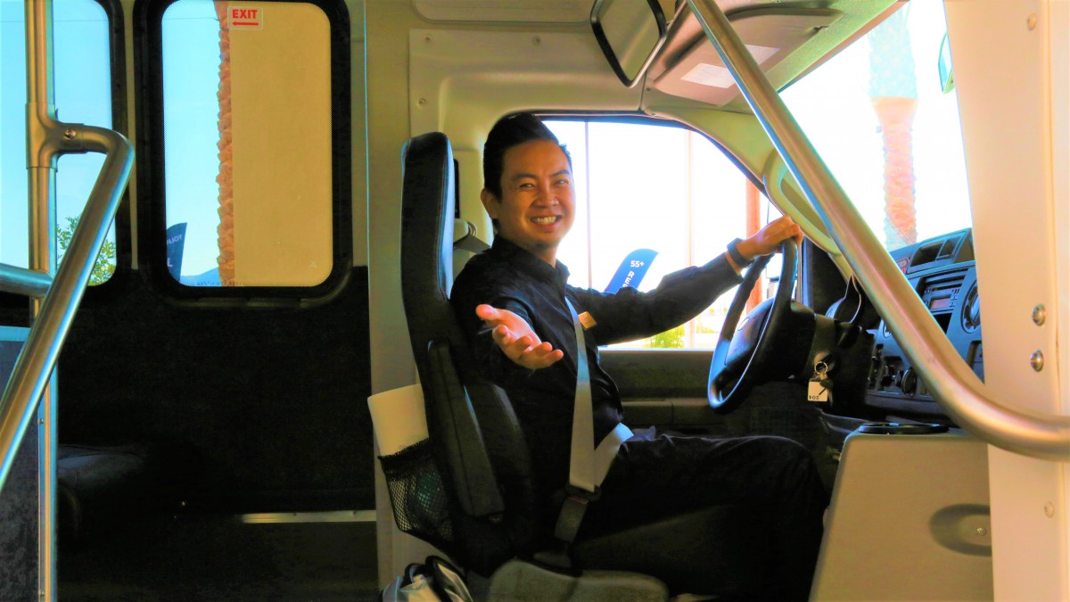 A person smiling while sitting in the driver's seat of a vehicle.