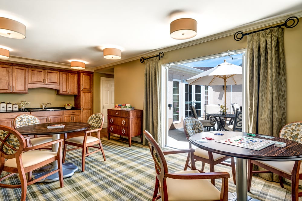 A cozy living space with a kitchenette and dining area, featuring patio doors that open to an outdoor seating area.