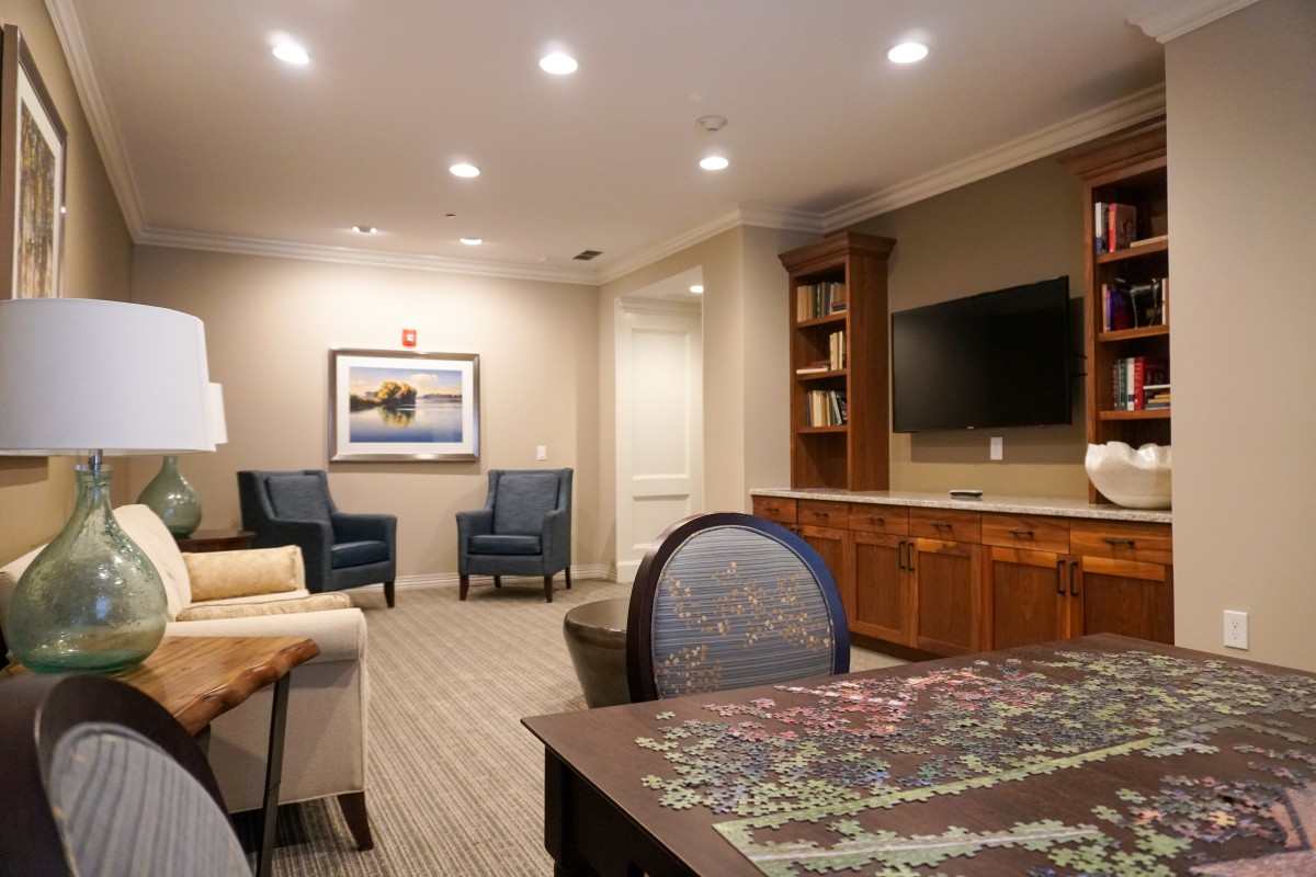 A cozy living room with a seating area, television, and bookshelf.