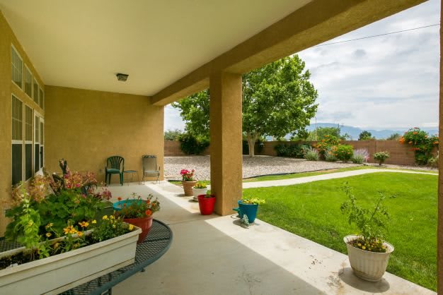 A cozy backyard patio with potted plants and comfortable seating overlooking a lush green lawn.