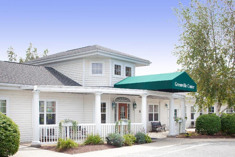 A two-story white building with a green awning over the entrance and well-maintained landscaping.