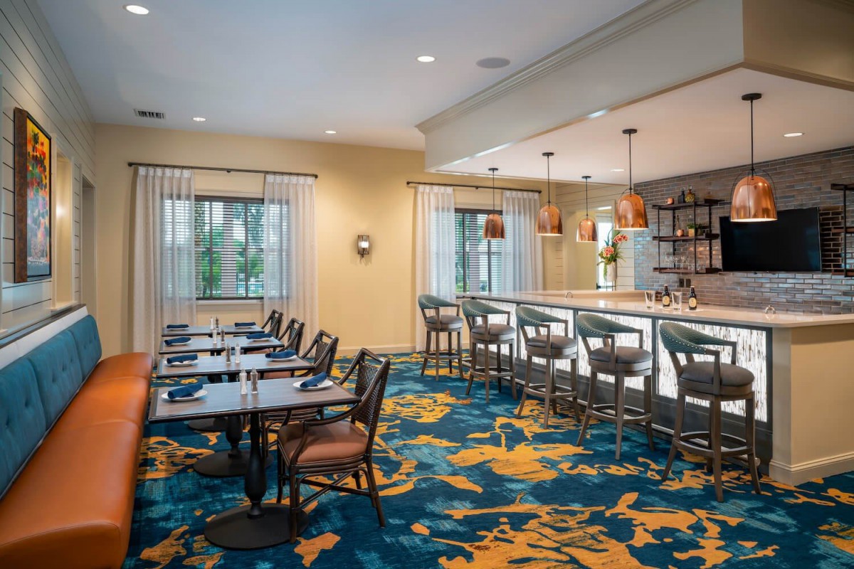 A modern restaurant interior featuring a dining area and bar.