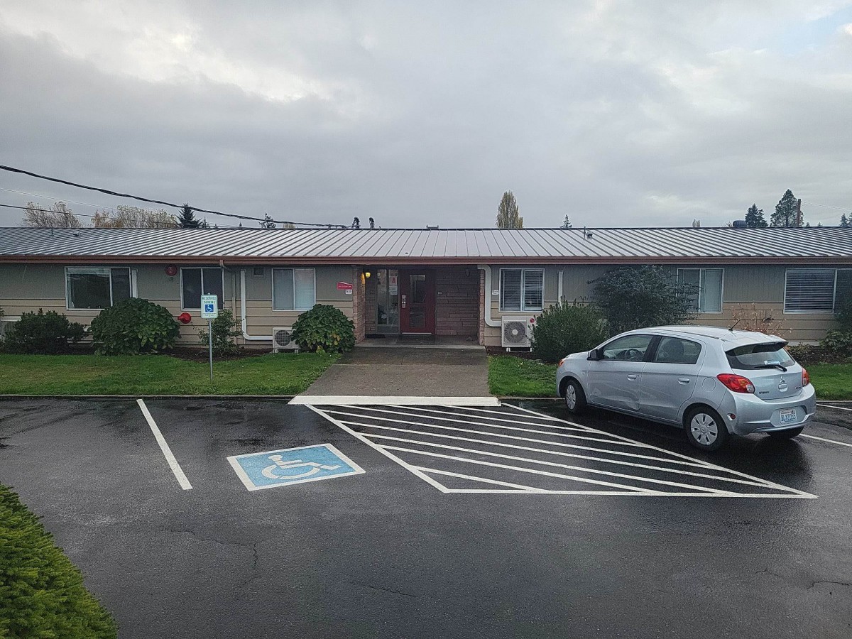 A small building with a parked car and handicap parking under an overcast sky.