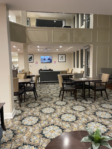 A cozy and modern dining area featuring tables, chairs, and a television in the background.