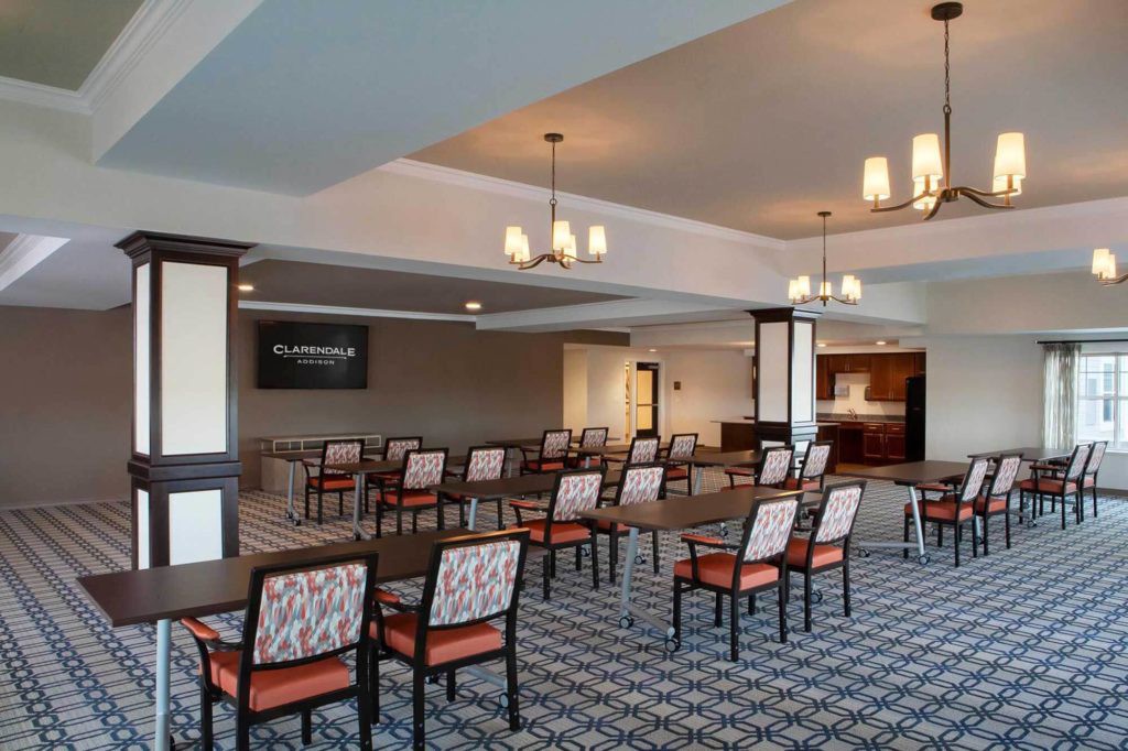 A well-lit conference room with arranged chairs and a presentation screen.