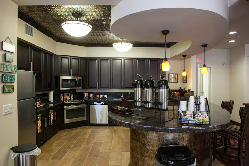 A modern kitchen featuring dark cabinets, a granite countertop, and a well-equipped coffee station.